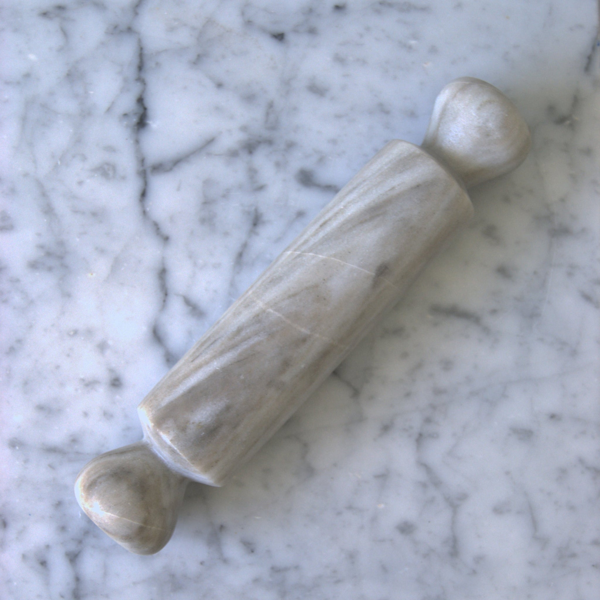 Two stone rolling pins on a marble surface
